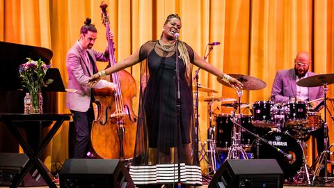 A singer performs in front of a bass and a pianist