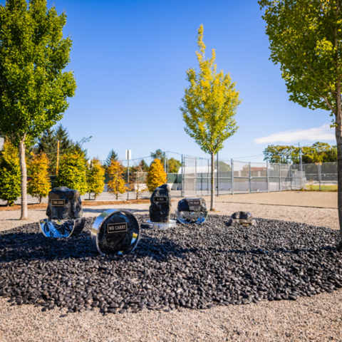 Yard with rocks and a tire rim with plaques with quotes from Amanda Gorman's poem "The Hill We Climb"