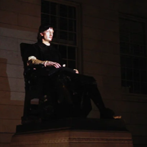 John Harvard statue with a projection of a student on top of it