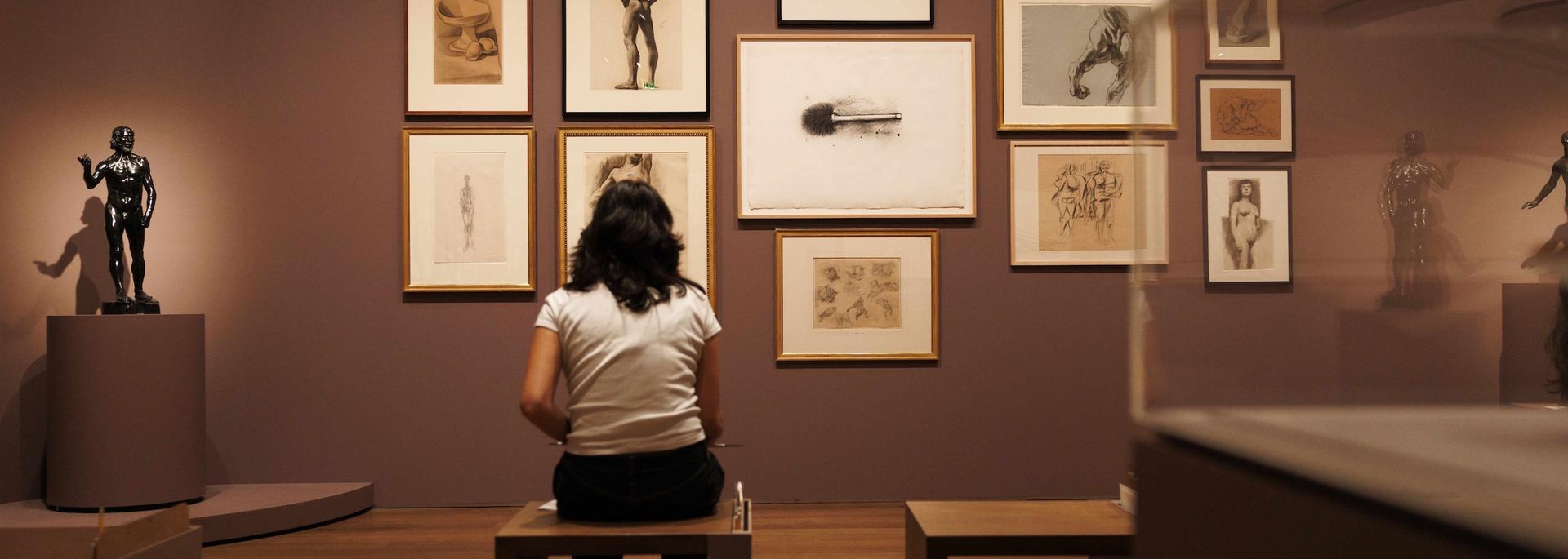 a woman looking at drawings in an art gallery