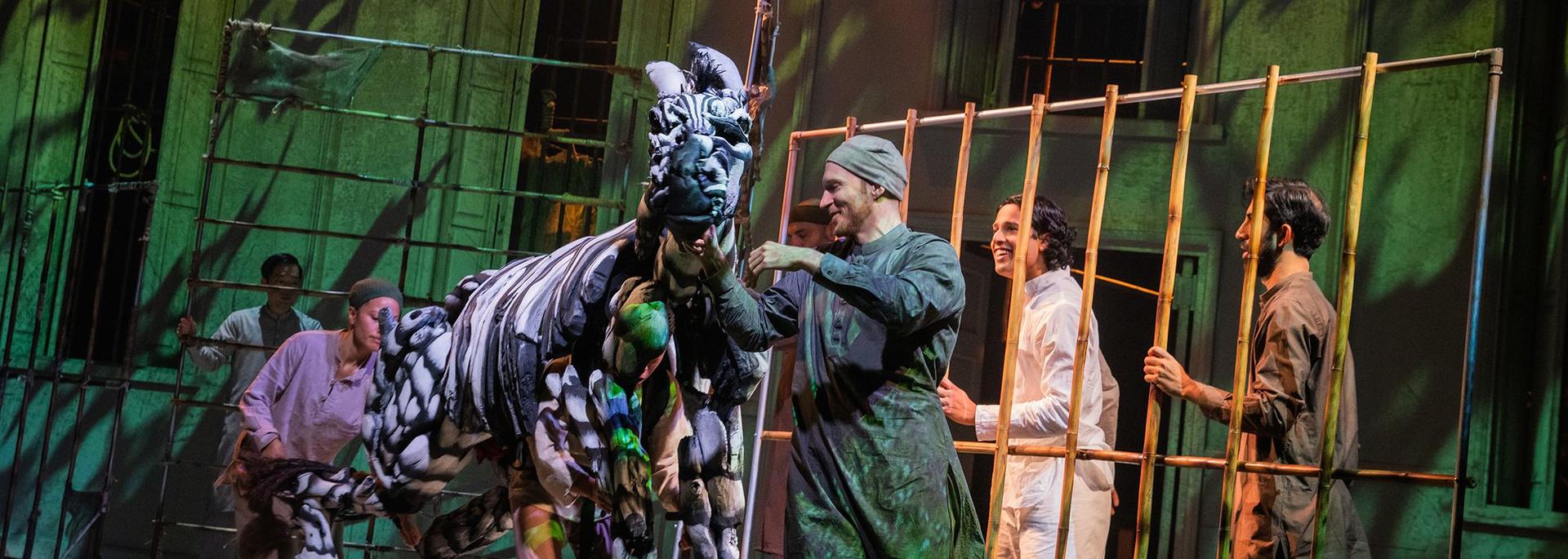 A zebra puppet and actors perform onstage in Life of Pi
